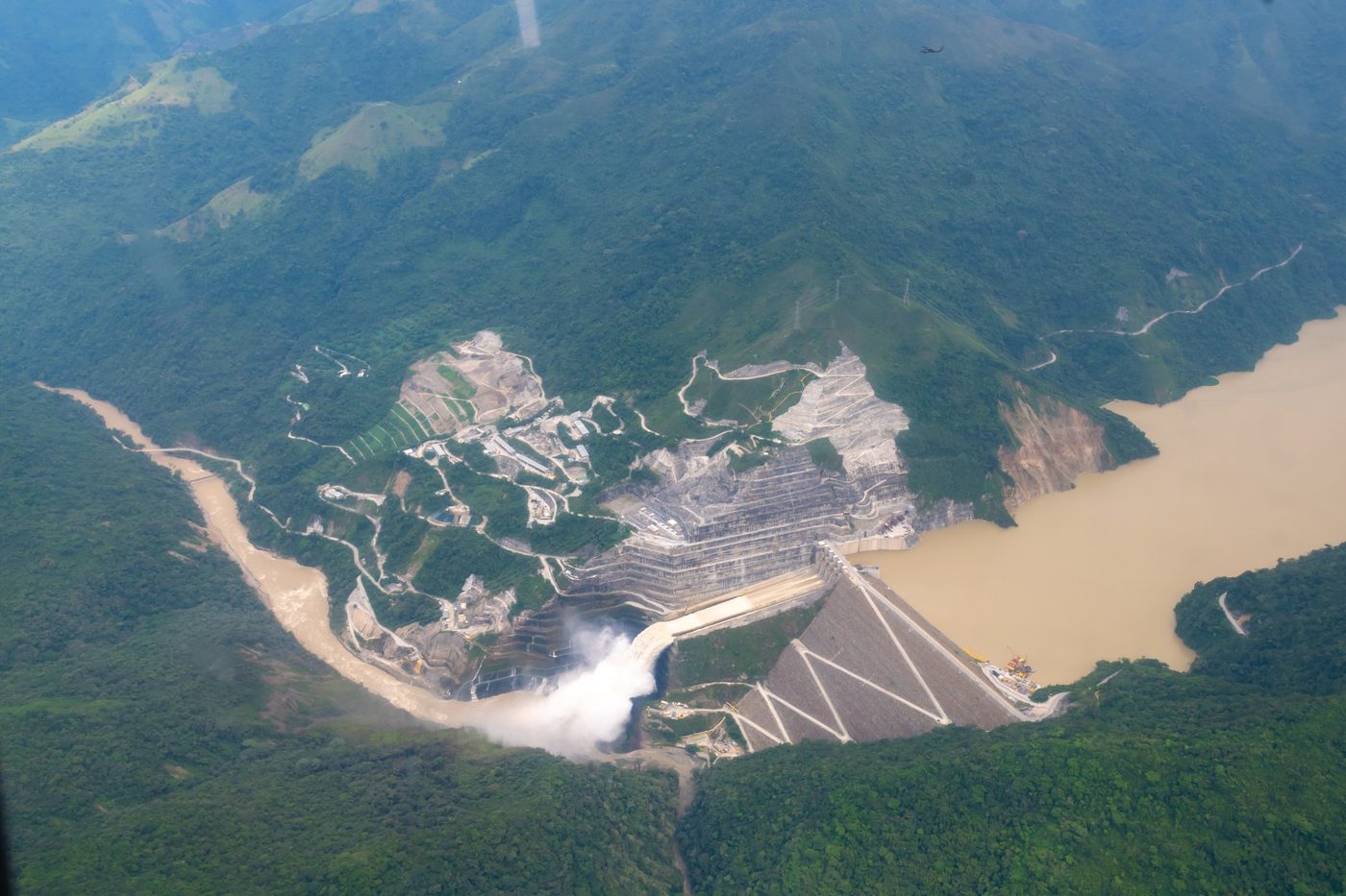 Vista aérea de una presa y su embalse entre montañas cubiertas de bosque