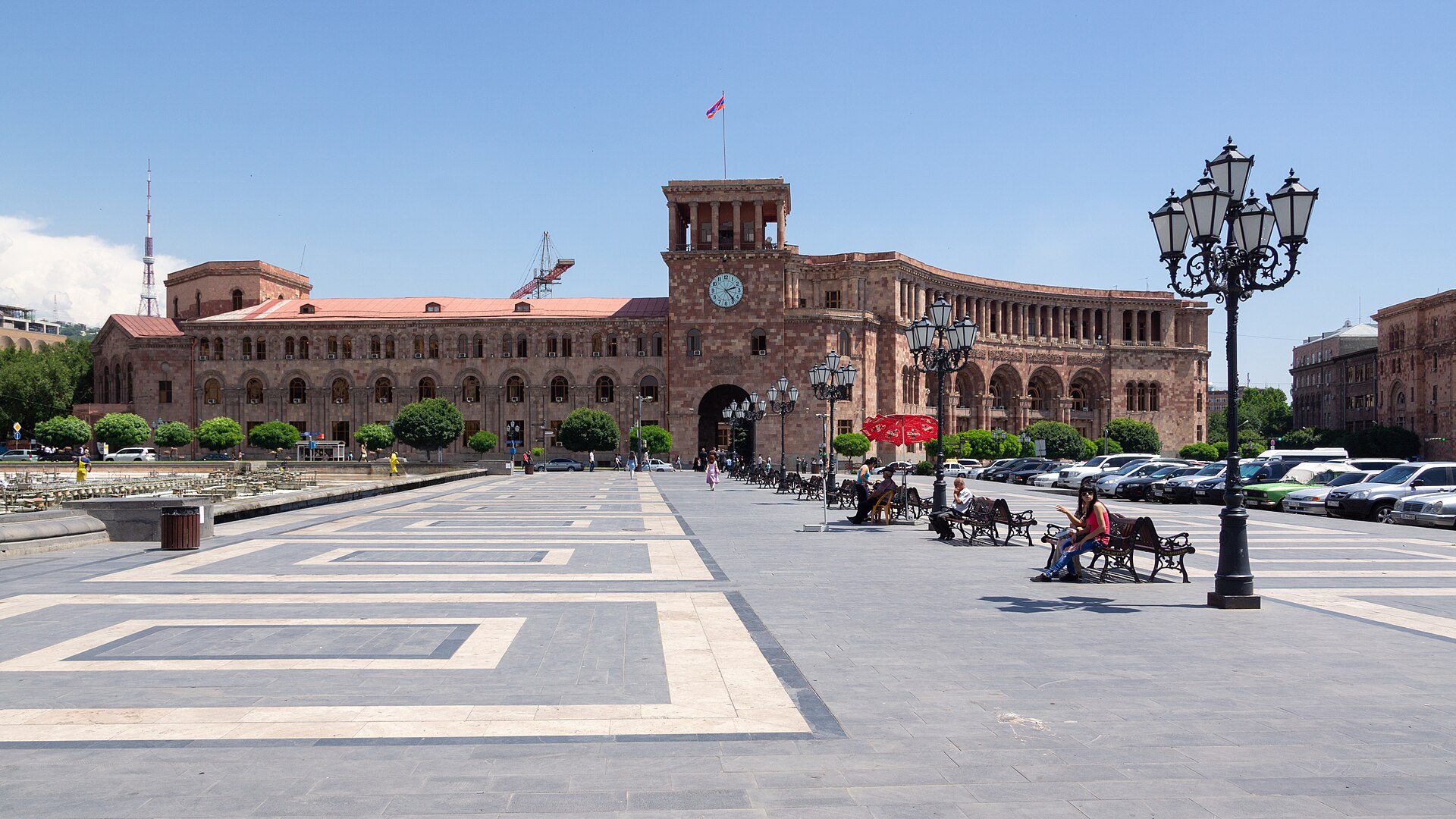 Edificio del Gobierno de Armenia, de piedra rojiza con torre de reloj, frente a una amplia plaza en Ereván bajo cielo despejado